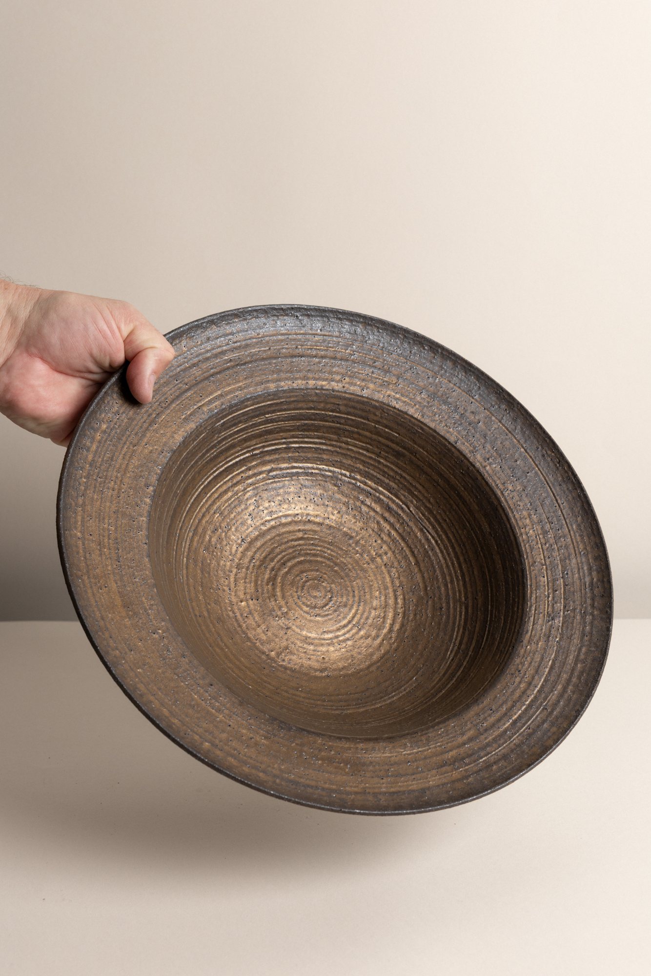 A wide bronze-glazed bowl held up to the light