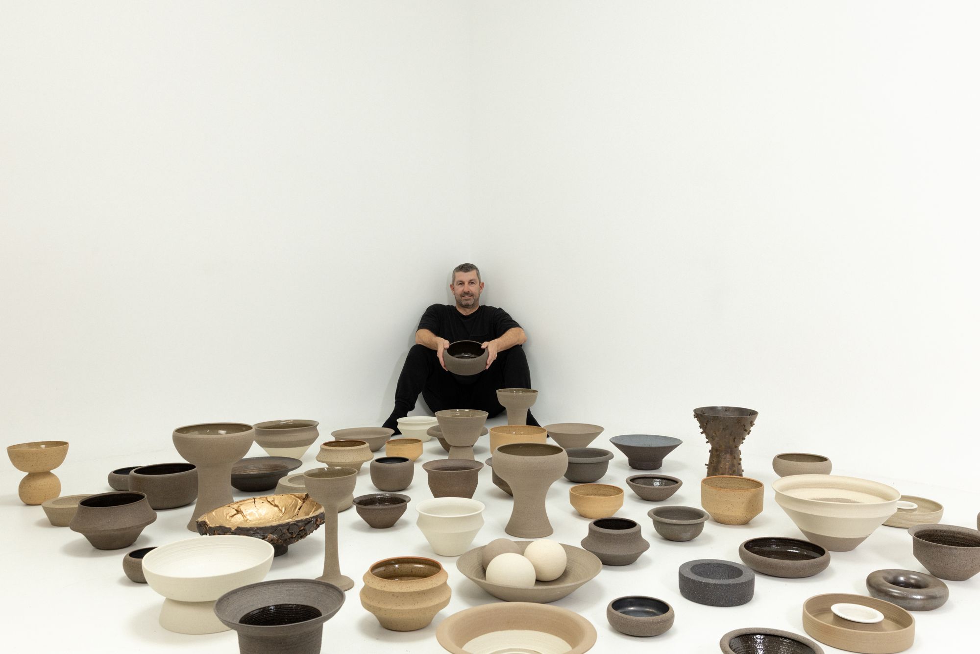 Craig Spencer seated among a floor of handmade bowls and vessels