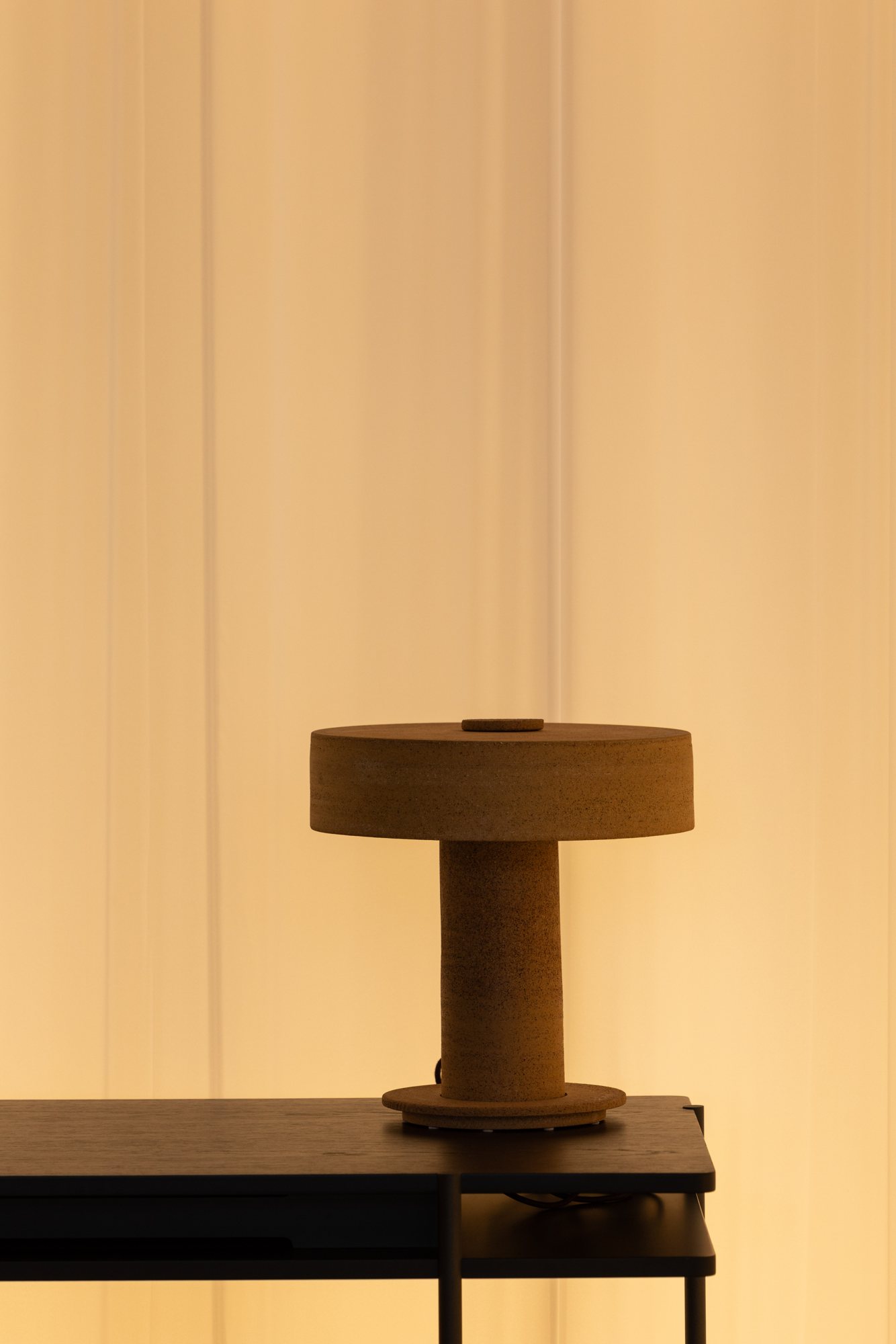 A ceramic table lamp glowing against a golden curtain